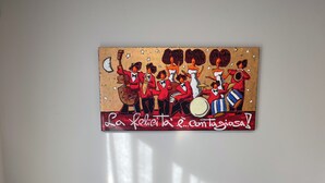 Quarto com um grande mural na parede, duas cadeiras, uma mesa redonda e um aquecedor vertical.