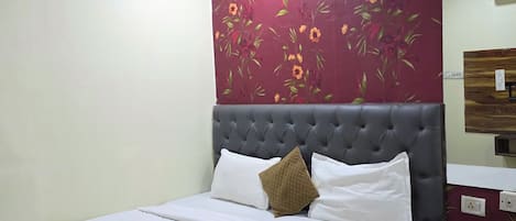 Un dormitorio con cama, ventilador de techo, papel tapiz floral y cabecera de madera.
