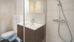 A modern bathroom with a toilet, a sink with a mirror, and a shower. - Elegant City Hub for 8 With Terrace (Antwerp)