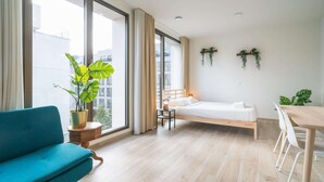 A modern room with a bed, a dining table, a blue sofa, and large windows. - Elegant City Hub for 8 With Terrace (Antwerp)
