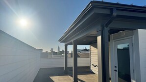 A rooftop terrace with a city skyline view, a covered seating area, and a door to a room. - 5-Min to the FIFA World Cup Games: Rooftop Patio + City Views (Atlanta)