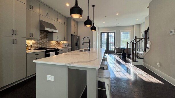 A modern kitchen with a central island, pendant lights, and a view to the dining area. - 5-Min to the FIFA World Cup Games: Rooftop Patio + City Views (Atlanta)