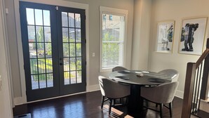 A dining area with a round table, chairs, and a view through a door to a garden. - 5-Min to the FIFA World Cup Games: Rooftop Patio + City Views (Atlanta)