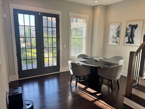 A dining area with a round table, chairs, and a view through a door to a garden. - 5-Min to the FIFA World Cup Games: Rooftop Patio + City Views (Atlanta)