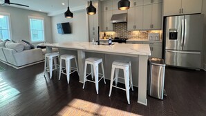 A modern kitchen with a central island, bar stools, stainless steel appliances, and a ceiling fan. - 5-Min to the FIFA World Cup Games: Rooftop Patio + City Views (Atlanta)