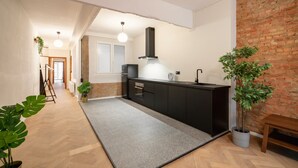 Moderni keittiö, jossa on keskellä sijaitseva saareke, tiiliseinä ja puulattia.