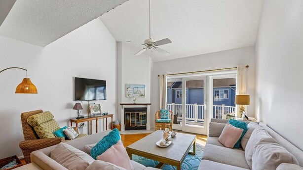 Een woonkamer met een bank, een salontafel, een televisie, een open haard en een balkon met uitzicht.