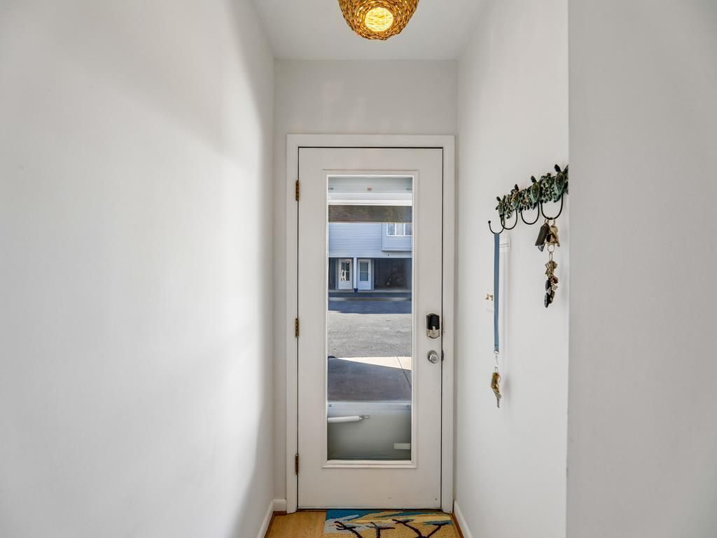 Un pasillo con una puerta blanca, un tapete pequeño y un llavero en la pared.