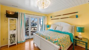 Een slaapkamer met een bed, een televisie, een raam en uitzicht op buiten.