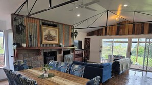 A spacious living area with a wooden dining table, blue patterned chairs, a blue sofa, and a fireplace.