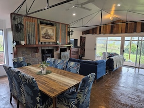 A spacious living area with a wooden dining table, blue patterned chairs, a blue sofa, and a fireplace.