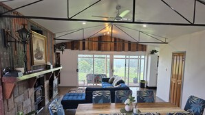A spacious living area with a fireplace, a dining table with chairs, a sofa, and a view through large sliding glass doors to the outdoors.