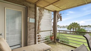 A balcony with a view of a body of water, a wooden railing, and a potted plant. - Needle Rush Point E13 (Pensacola)