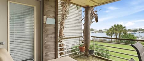 A balcony with a view of a body of water, a wooden railing, and a potted plant.