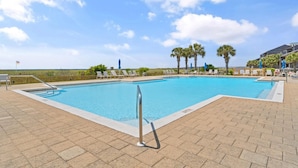 A rectangular swimming pool with a tiled deck, surrounded by lounge chairs and palm trees. - Needle Rush Point E13 (Pensacola)