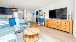 Ein modernes Wohnzimmer mit einer Couch, Couchtisch, Fernseher, Holzschrank und Kunstwerken an der Wand.