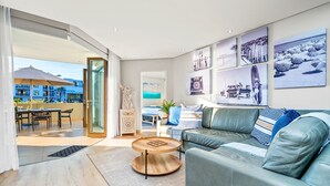 Ein modernes Wohnzimmer mit einem grünen Sofa, einem runden Couchtisch und einem Essbereich mit Tisch und Stühlen.