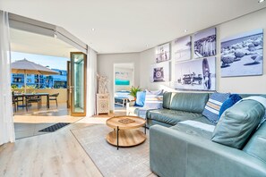 A modern living room with a green sofa, a round coffee table, and a dining area with a table and chairs. - Ocean Mist 105 (Cape Town)