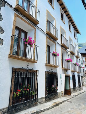 A multi-story building with balconies, potted plants, and a sign indicating a restaurant. - Hostal Pirineos Meliz (Bielsa)