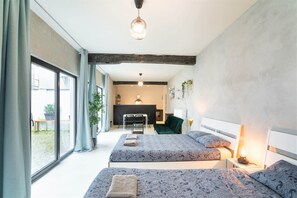 A modern bedroom with two beds, a desk, and a fireplace. - Antwerp Central 1br/7p Apartment (Antwerp)