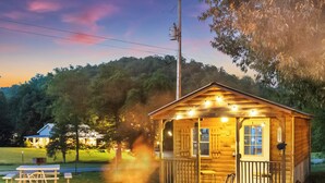 A wooden cabin with a fire pit, outdoor seating, and a sign that reads 'Yeti to Sleep.'
