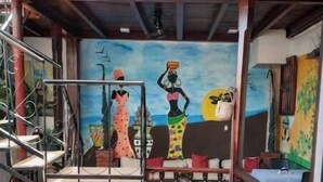 Una escalera con barandilla, un mural con figuras y plantas en macetas.