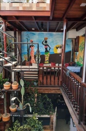 Eine Treppe mit Geländer, ein Wandbild mit Figuren und Topfpflanzen.