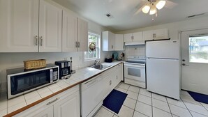 A kitchen with white cabinets, a microwave, a coffee maker, a stove, and a refrigerator.