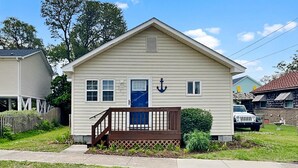 A single-story house with a front porch, a blue door, and a small garden area.