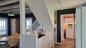 A modern kitchen with white cabinetry, a built-in stove, and a dining area with a wooden table and chairs.