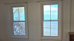 Una camera da letto con un letto, due finestre, una cassettiera in legno e una lampada a soffitto.