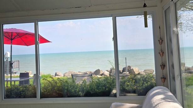 Una stanza con vista sul mare, un ombrellone rosso e un divano con cuscini.