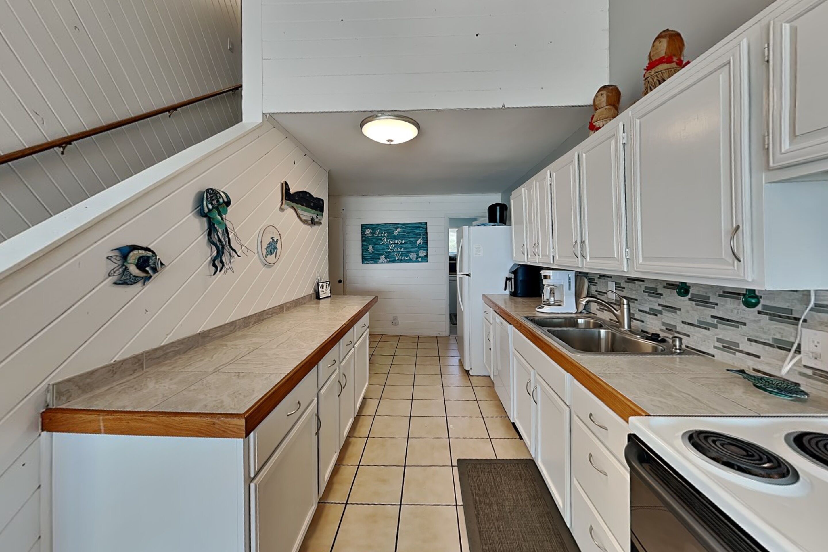 A kitchen with white cabinets, a tiled floor, a wooden countertop, and a stove.