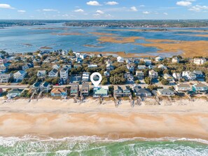 An aerial view of a coastal residential area with houses, a beach, and a body of water. - Take Me A Wave (Holly Ridge)