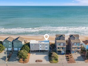 A coastal residential area with houses, a beach, and a large white location marker. - Take Me A Wave (Holly Ridge)