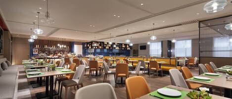 A modern dining area with multiple tables, chairs, and a bar area.
