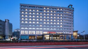Ein mehrstöckiges Hotel mit bogenförmiger Fassade, beleuchteten Fenstern und einer auffälligen Beschilderung.