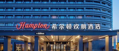 A modern hotel entrance with a prominent sign, large pillars, and a covered walkway.