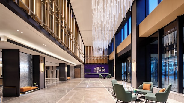 Eine geräumige Lobby mit hoher Decke, moderner Möblierung und einem großen Fenster mit Blick auf die Stadt.