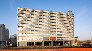 Un hotel de varios pisos con fachada curva, amplias ventanas y una entrada destacada.
