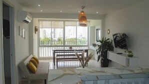 Una sala de estar moderna con una mesa de comedor, sofá y ventanas amplias.