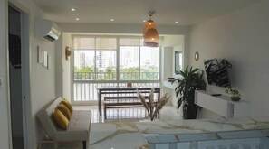 Ein modernes Wohnzimmer mit Esstisch, Sofa und großen Fenstern.