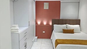 Un dormitorio con cama, mesita de noche, armario y aire acondicionado.