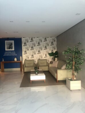 A modern living room with a sofa, coffee table, and a wall decorated with newspaper clippings. - Beautiful apartment with 2 bedrooms (1 suite), garage and mountain views. (Guarapari)