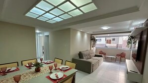 A dining area with a table set for four, a sofa, and a TV. - Recanto Nascer do Sol - your refuge in Cabedelo (Cabedelo)