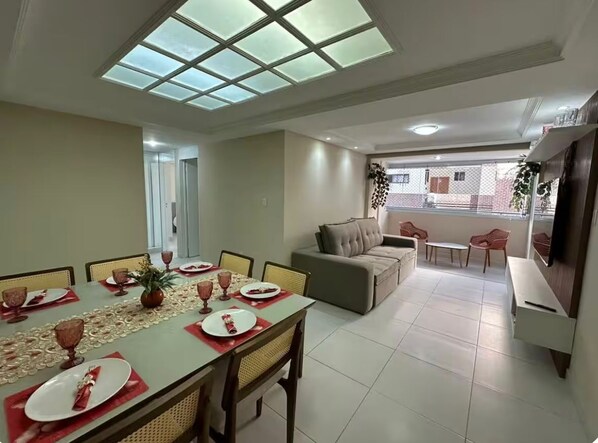 A dining area with a table set for four, a sofa, and a TV.