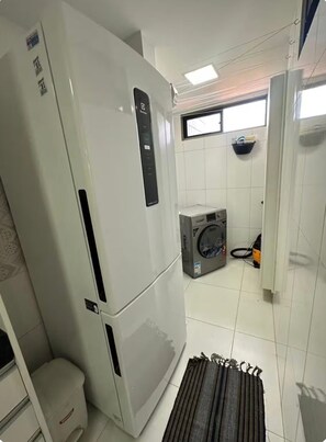 Una cocina compacta con un refrigerador blanco, una lavadora y un ventanal pequeño.