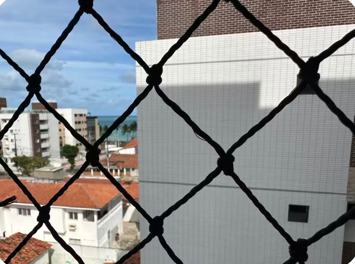 A chain-link fence with a view of buildings and a clear sky.