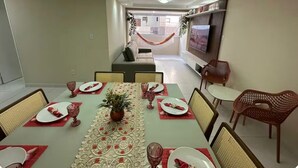 A dining area with a table set for four, chairs, a sofa, and a TV. - Recanto Nascer do Sol - your refuge in Cabedelo (Cabedelo)