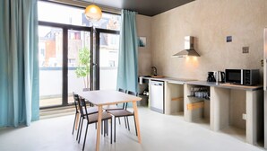 A modern kitchen with a dining area, a built-in microwave, and a coffee maker. - Antwerp Central Residence1bbknswifi (Antwerp)